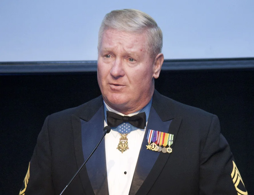Older man at podium wearing military medals