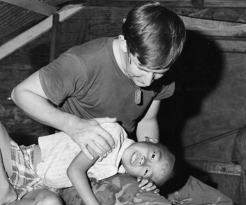 A man with his hand on a boy resting on his head on the man's lap