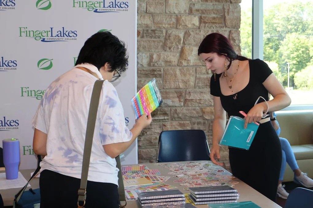 Two students grabbing planners and stickers.