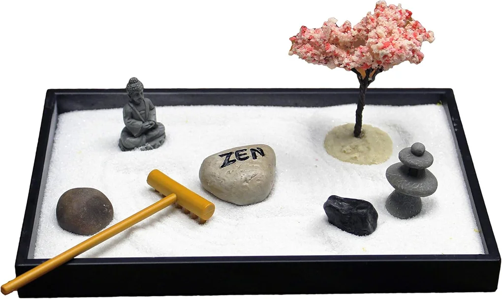 Miniature Zen garden with white sand, a Buddha statue, stones, a small tree, a rock labeled 