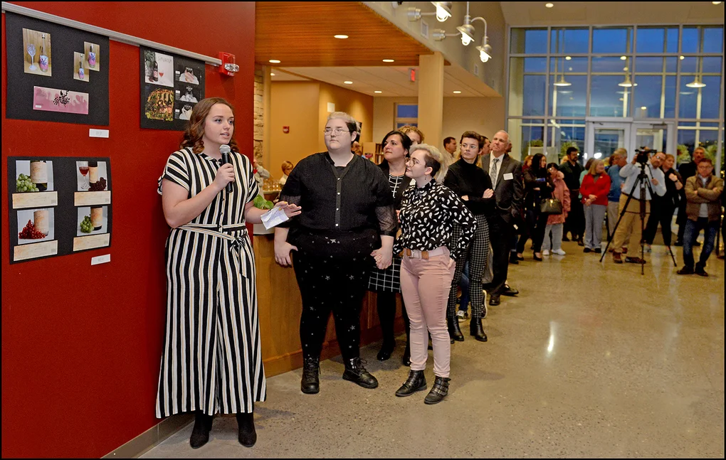 Student Rachel Graf presents her wine bottle label at a reception