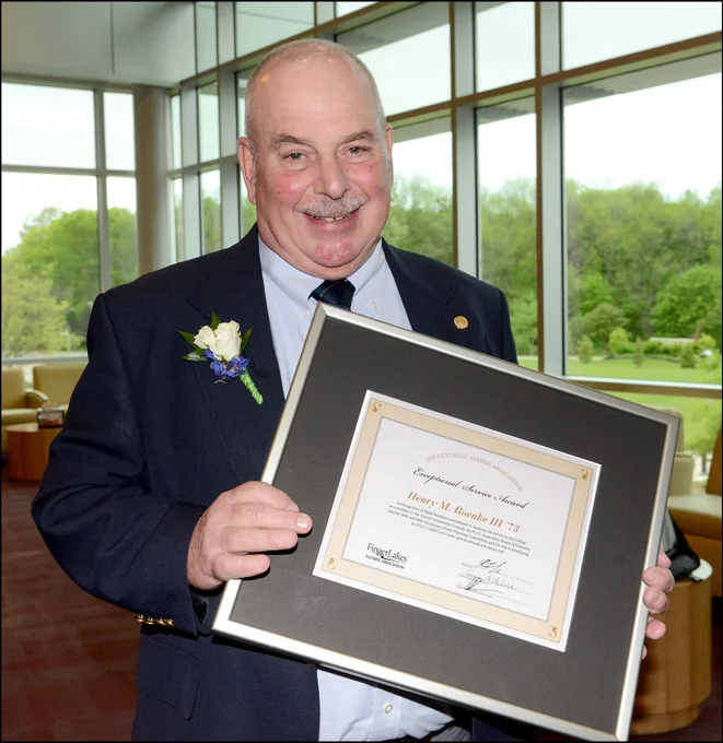 Man in a suit holding a framed award