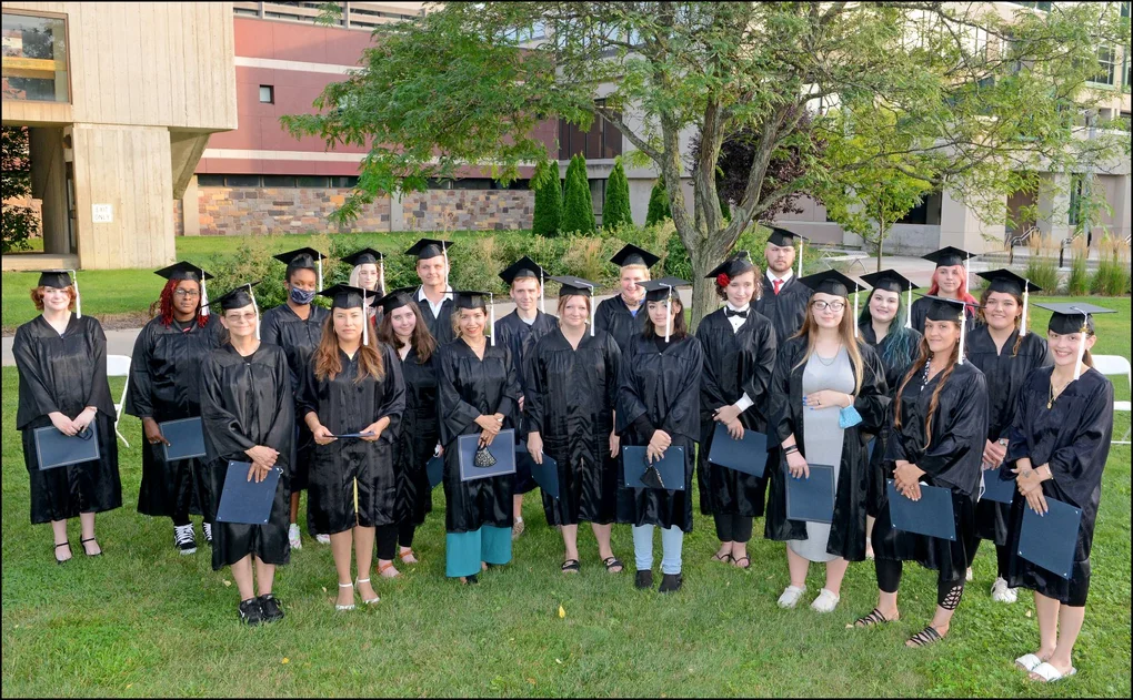 Graduates standing outside under a tree