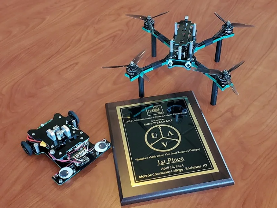 Student-made UAV and UGV with a first place plaque.