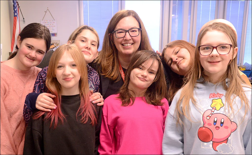 Female principal poses with several female middle school students