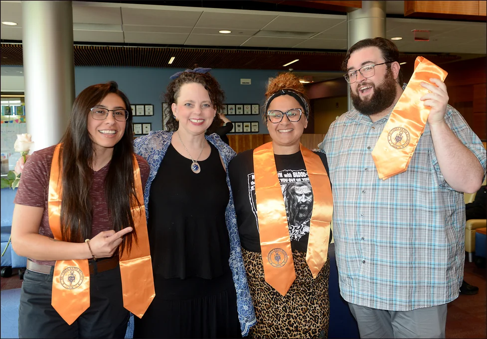 Four individuals posed for a photo with Phi Theta Kappa representative graduation stoles.