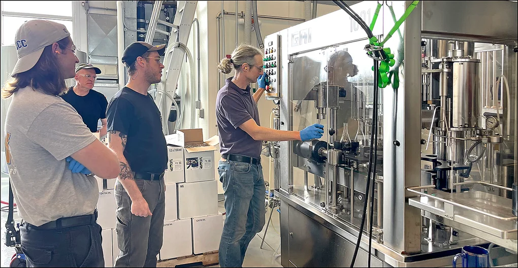 Instructor showing 3 students a wine bottling machine