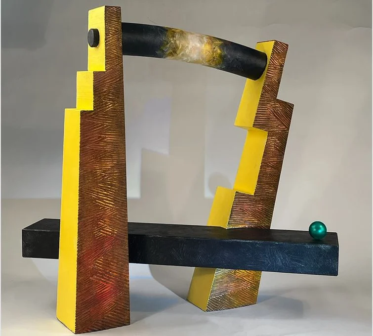 Abstract sculpture of two towers joined by plank with another plank near the bottom