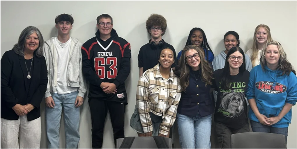 An adult and 10 teenagers smiling and standing in a row