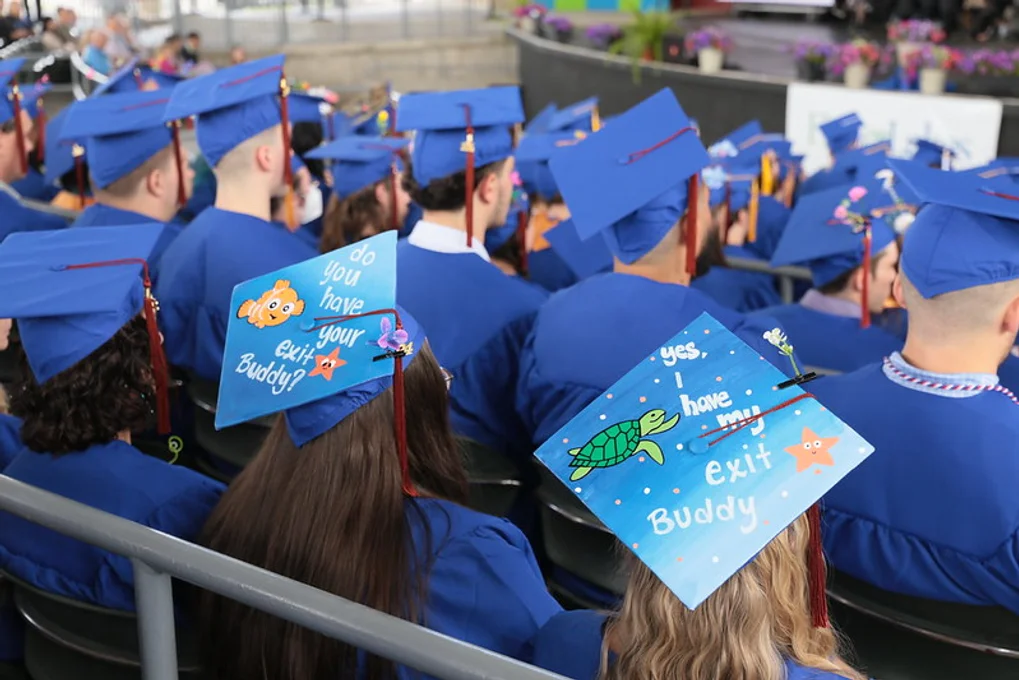 2 graduates wearing decorated mortarboards