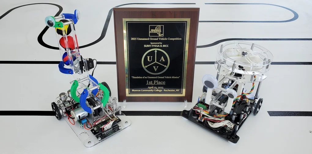 Two small wheeled robots on either side of an award plaque