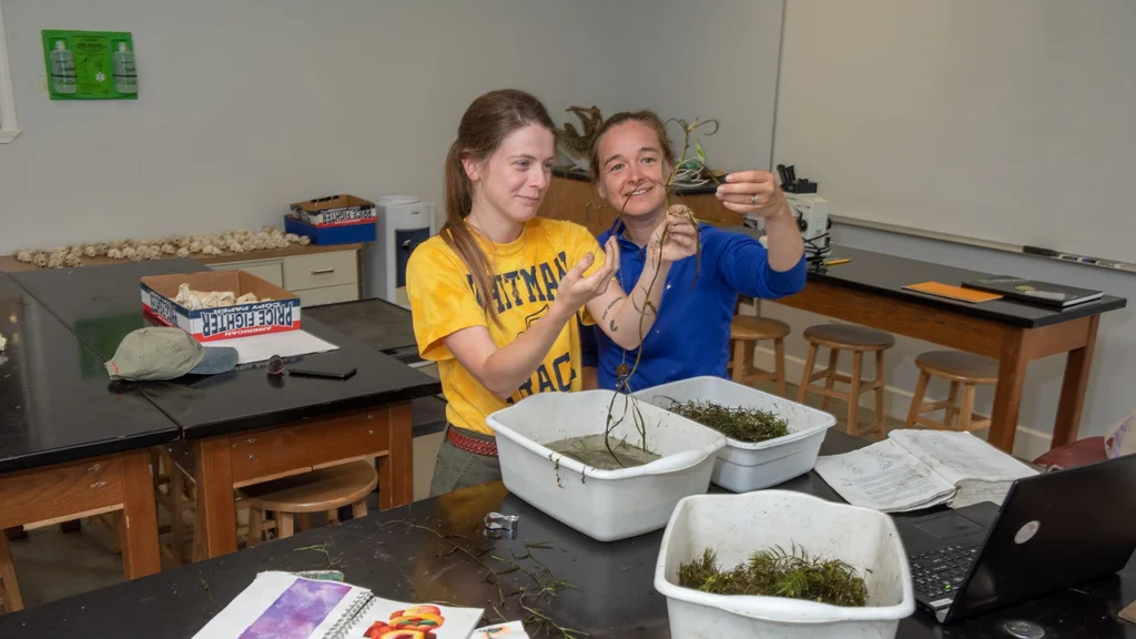 Two women examining tubs of aquatic plants