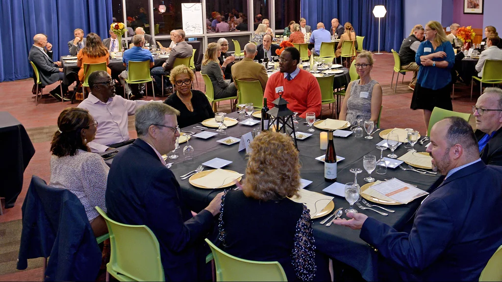 FLCC employees gathered around tables in a room, enjoying a meal together.