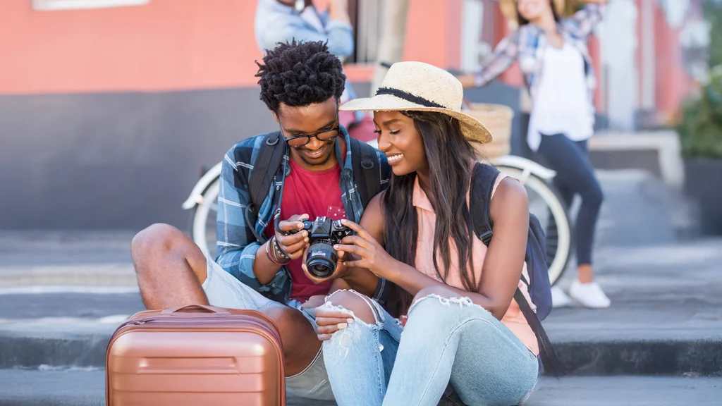 Two tourists exploring new places together pause momentarily to review photos on a camera.