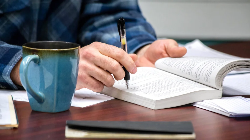 Student holding an open book reviewing highlighted text.