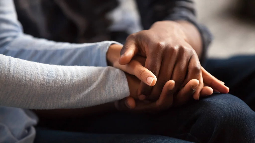 Three hands clasped together in a display of strength, support, and human connection.
