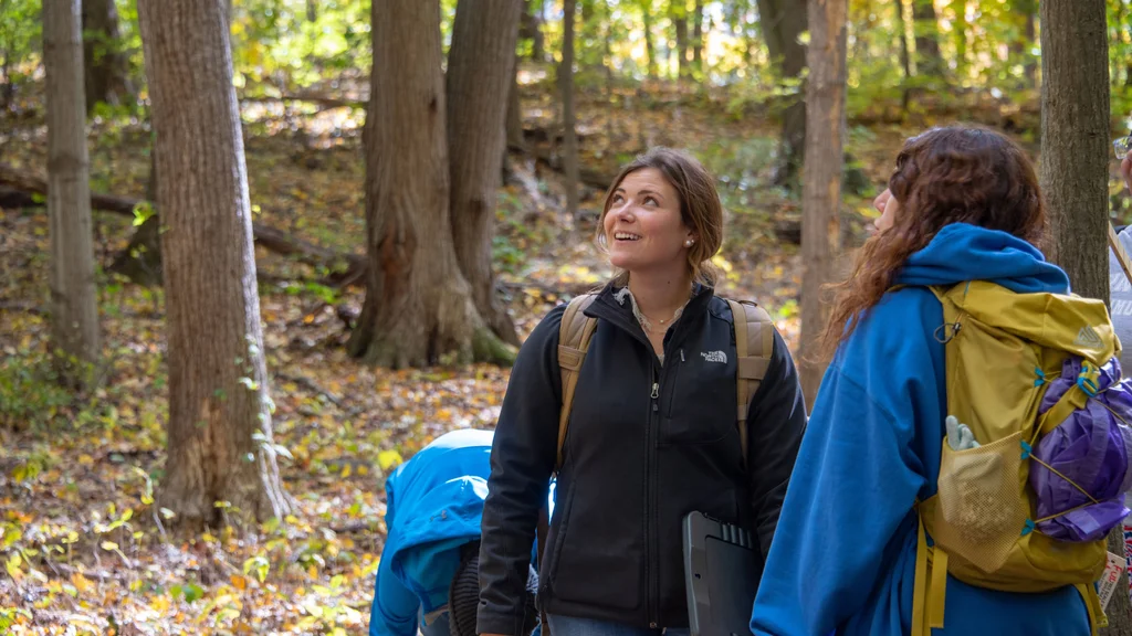 Two natural resources conservation students backpacking through a forest.