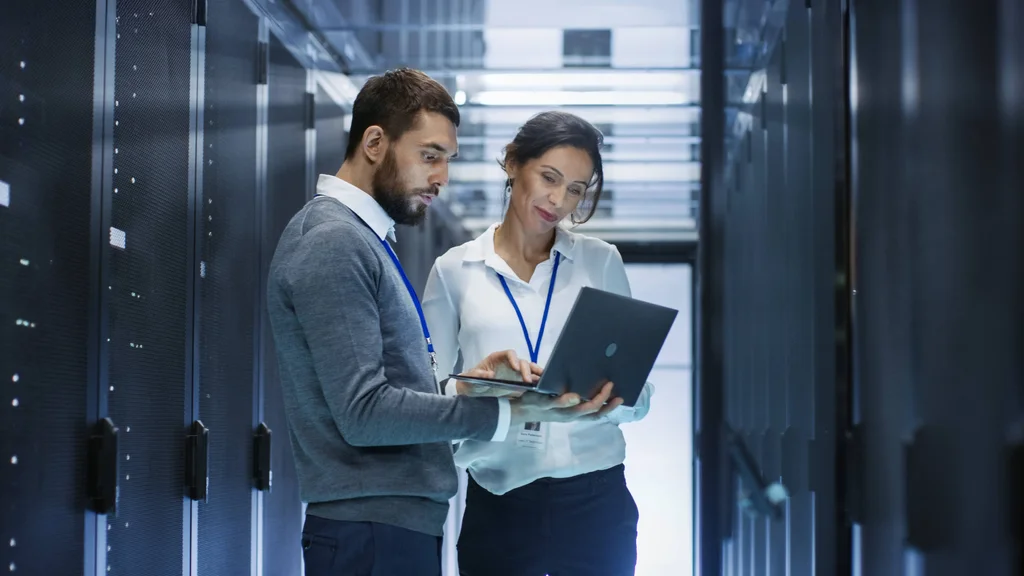 Two computing science professionals looking at a laptop screen.