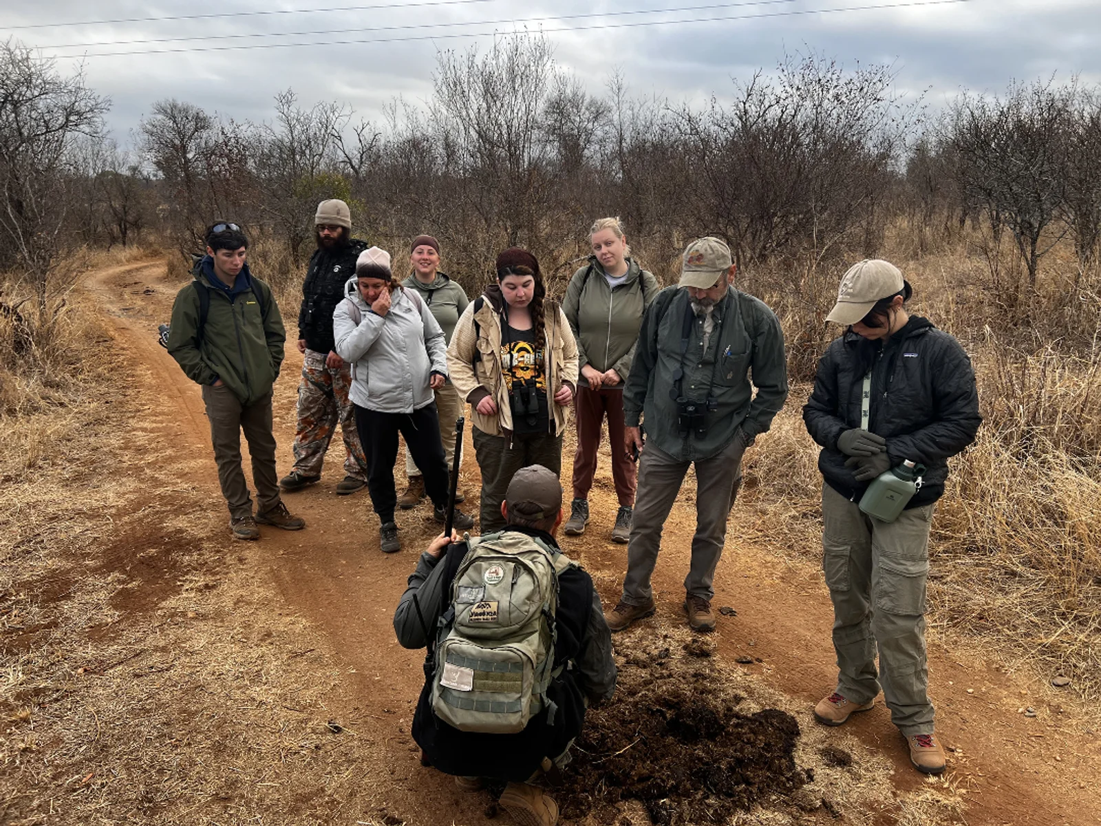 Faculty and students pose for a photo in front of a street sign.