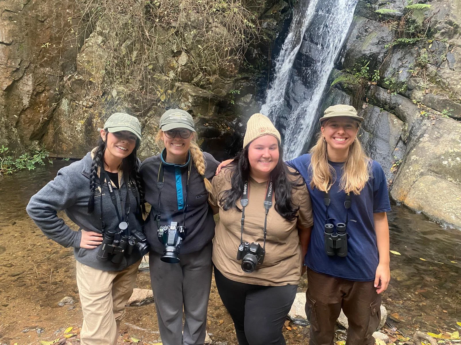 Faculty and students pose for a photo in front of a street sign.