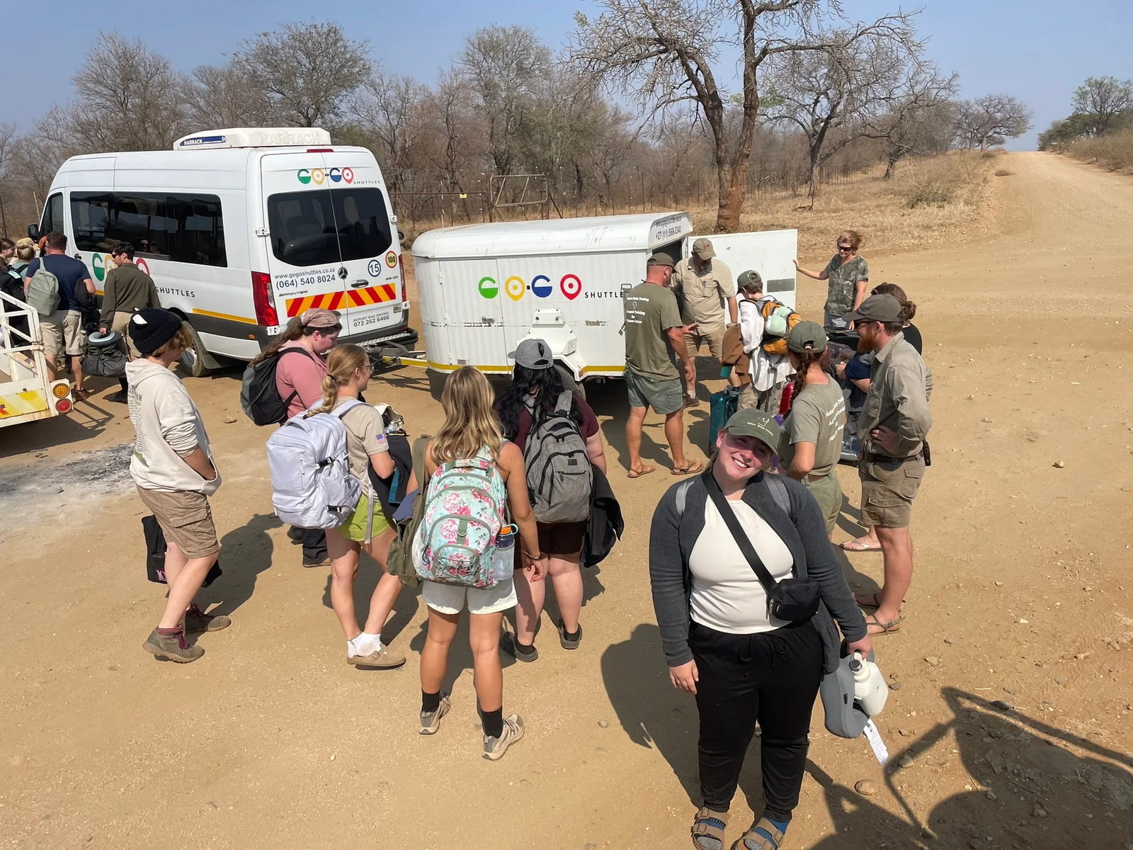 Faculty and students pose for a photo in front of a street sign.