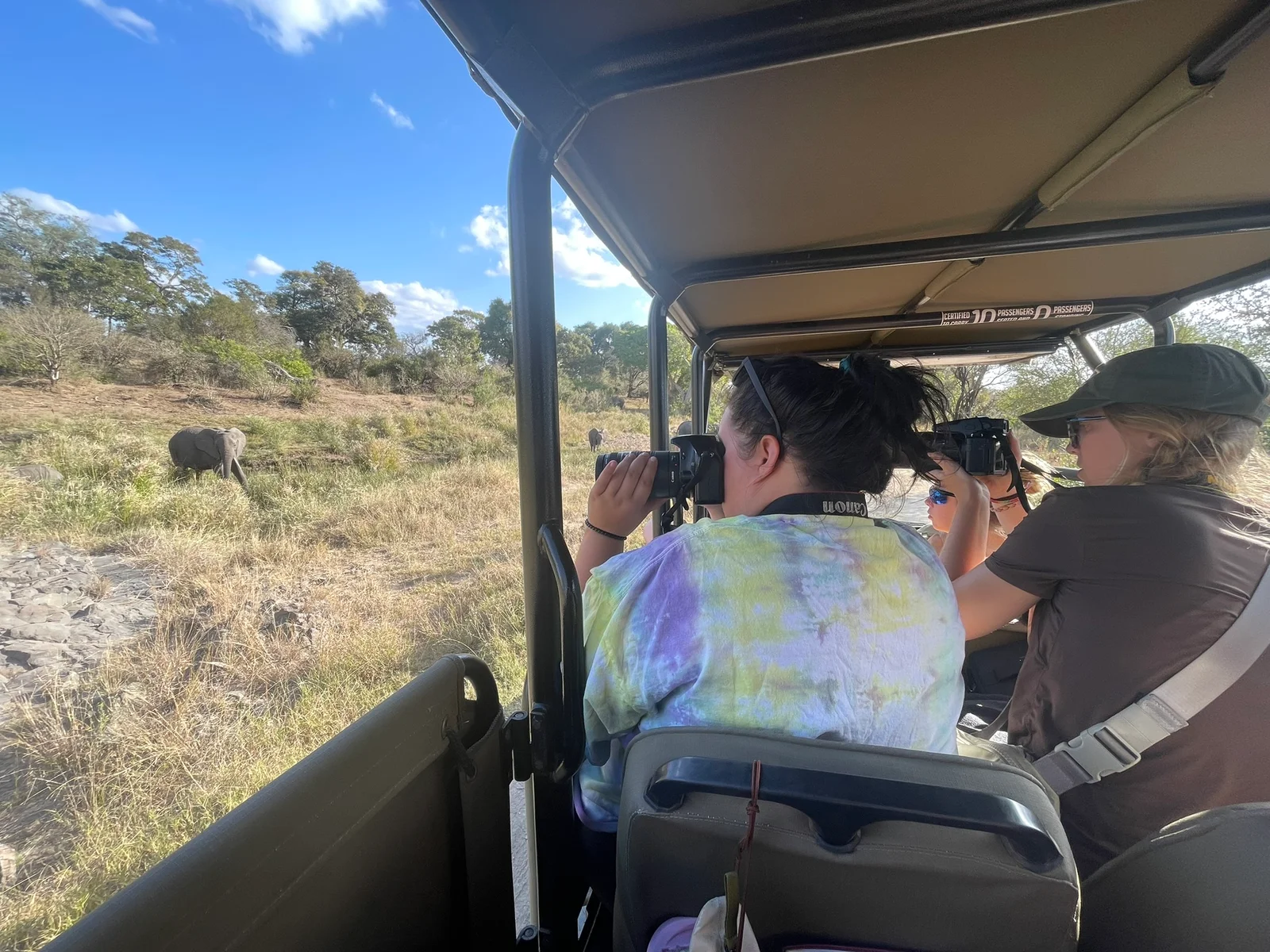 Faculty and students pose for a photo in front of a street sign.