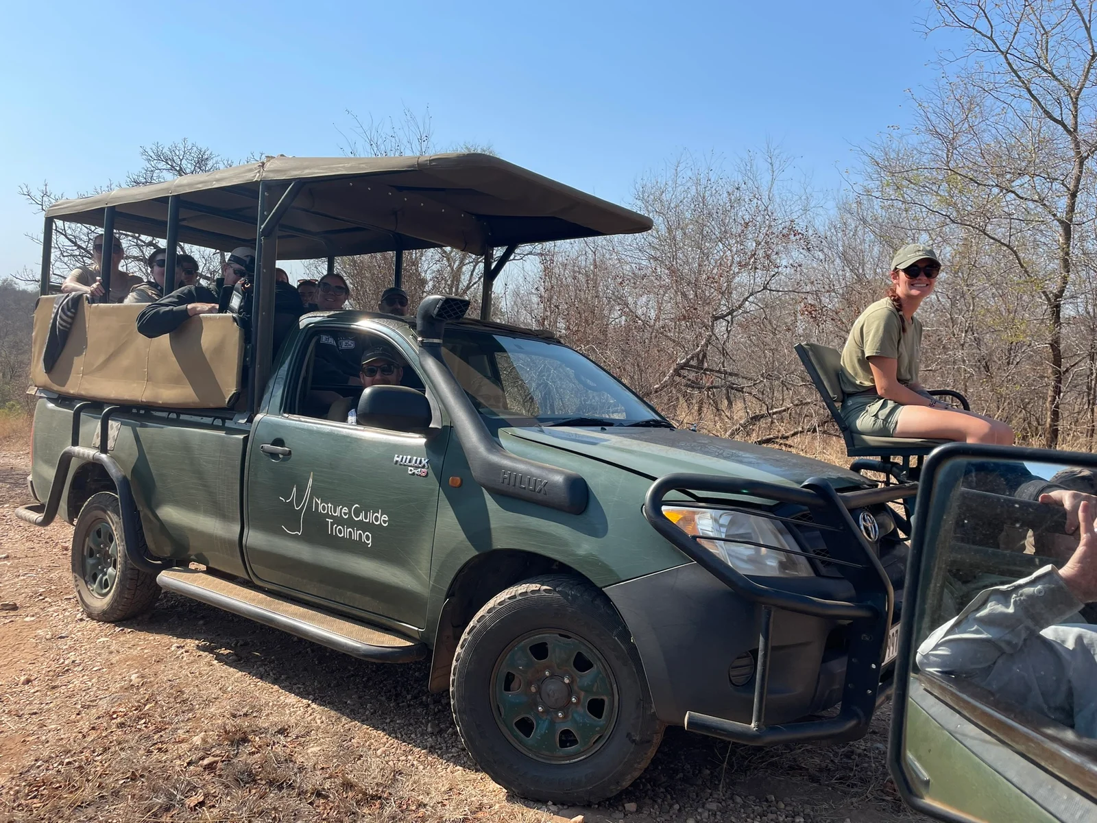 Faculty and students pose for a photo in front of a street sign.