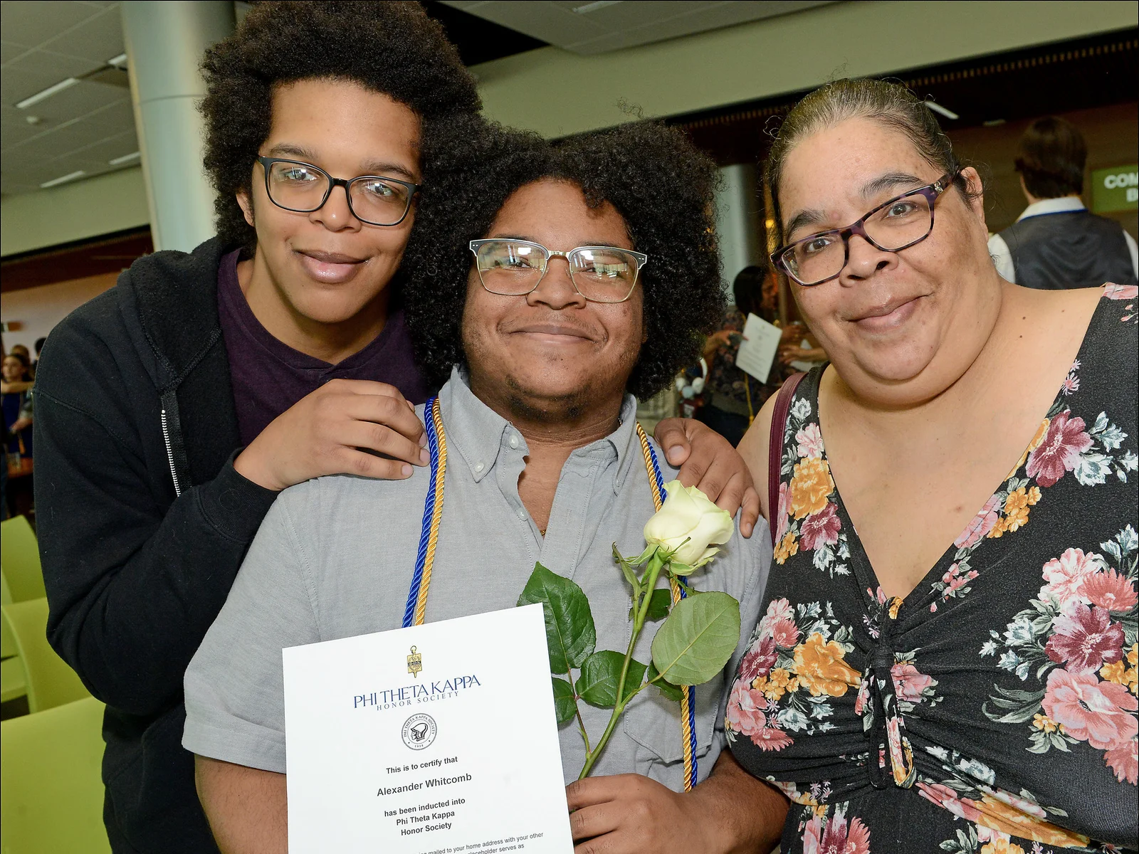 Student posing with PTK certificate and two family members