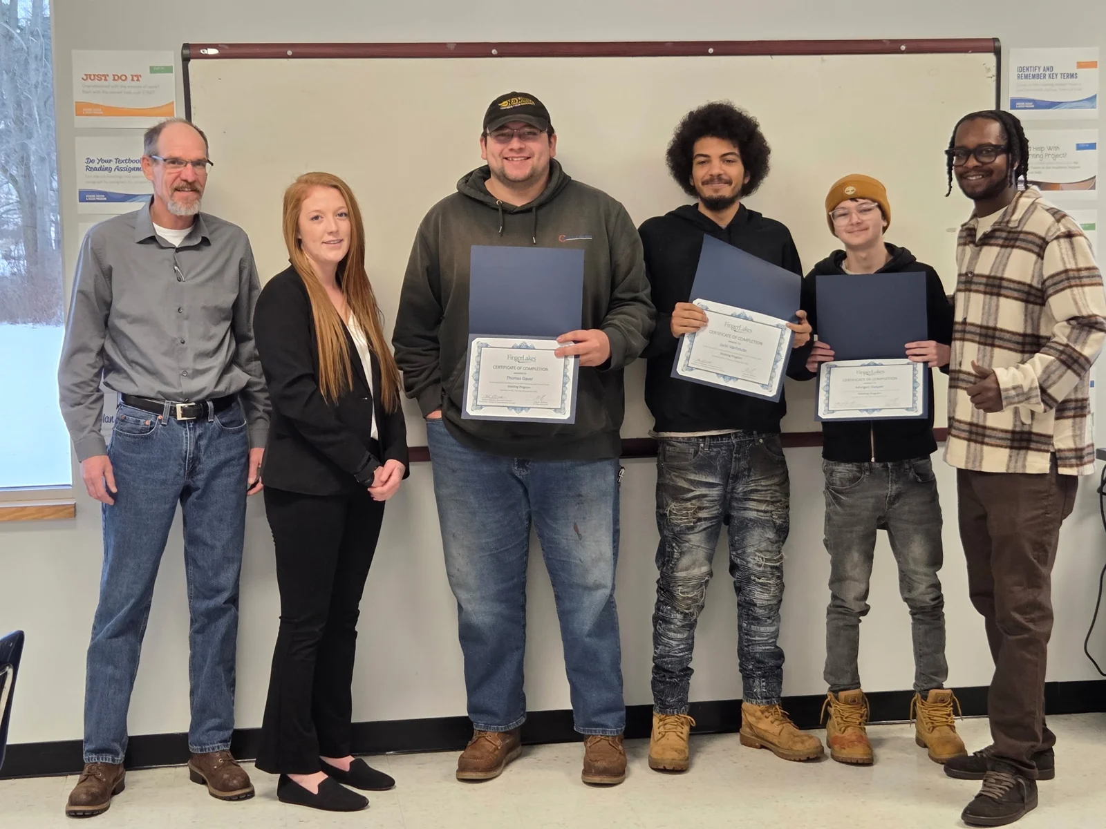 An instructor stands next to a man in a welding helmet using computer simulation technology