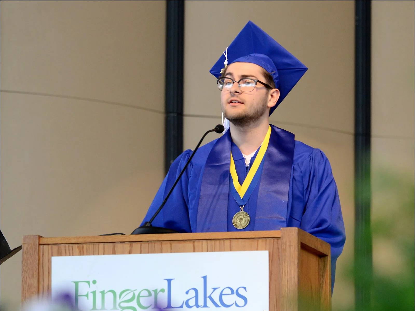 J. Naused at podium in regalia