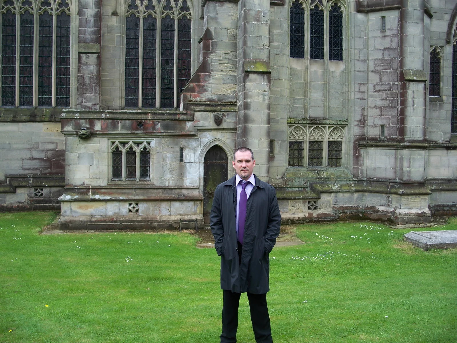 Man weariong a suit, standing in the grass
