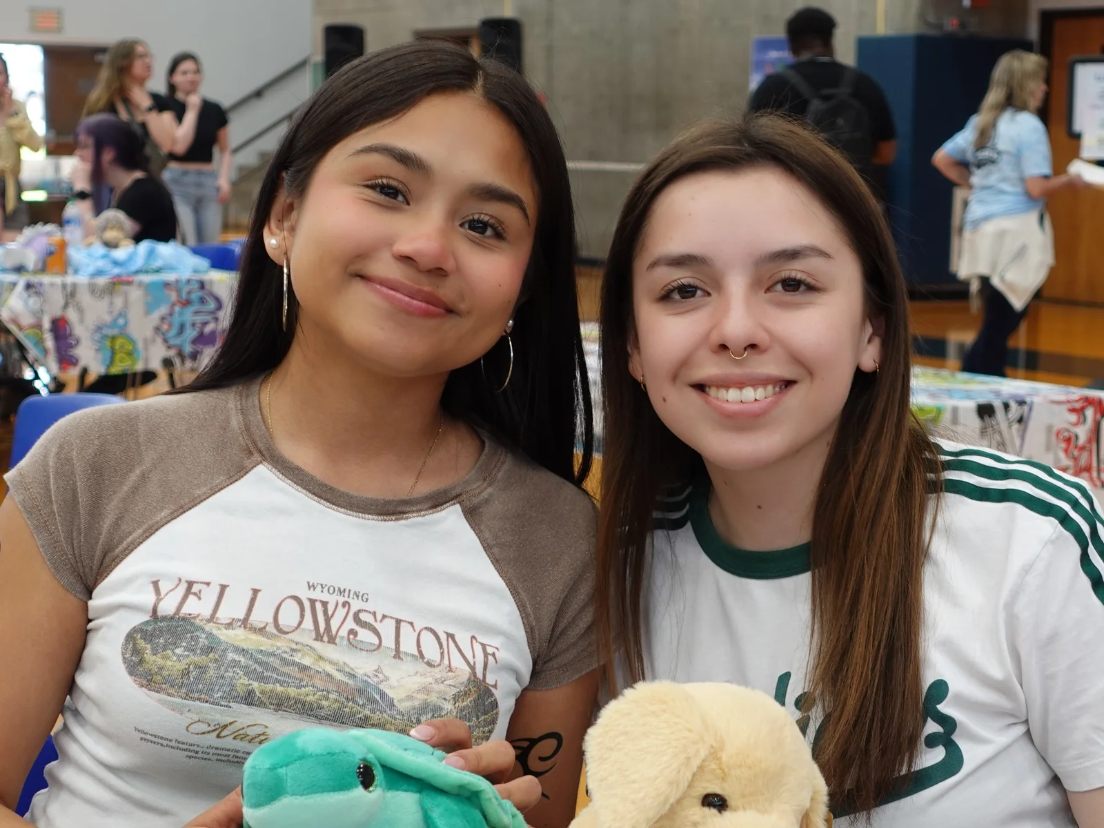 Two students sitting at a table and smiling at the camera for a posed photo