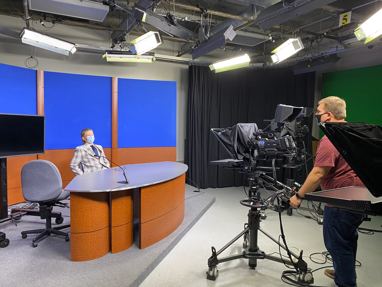 Cameraman filming FLCC student behind desk in TV studio