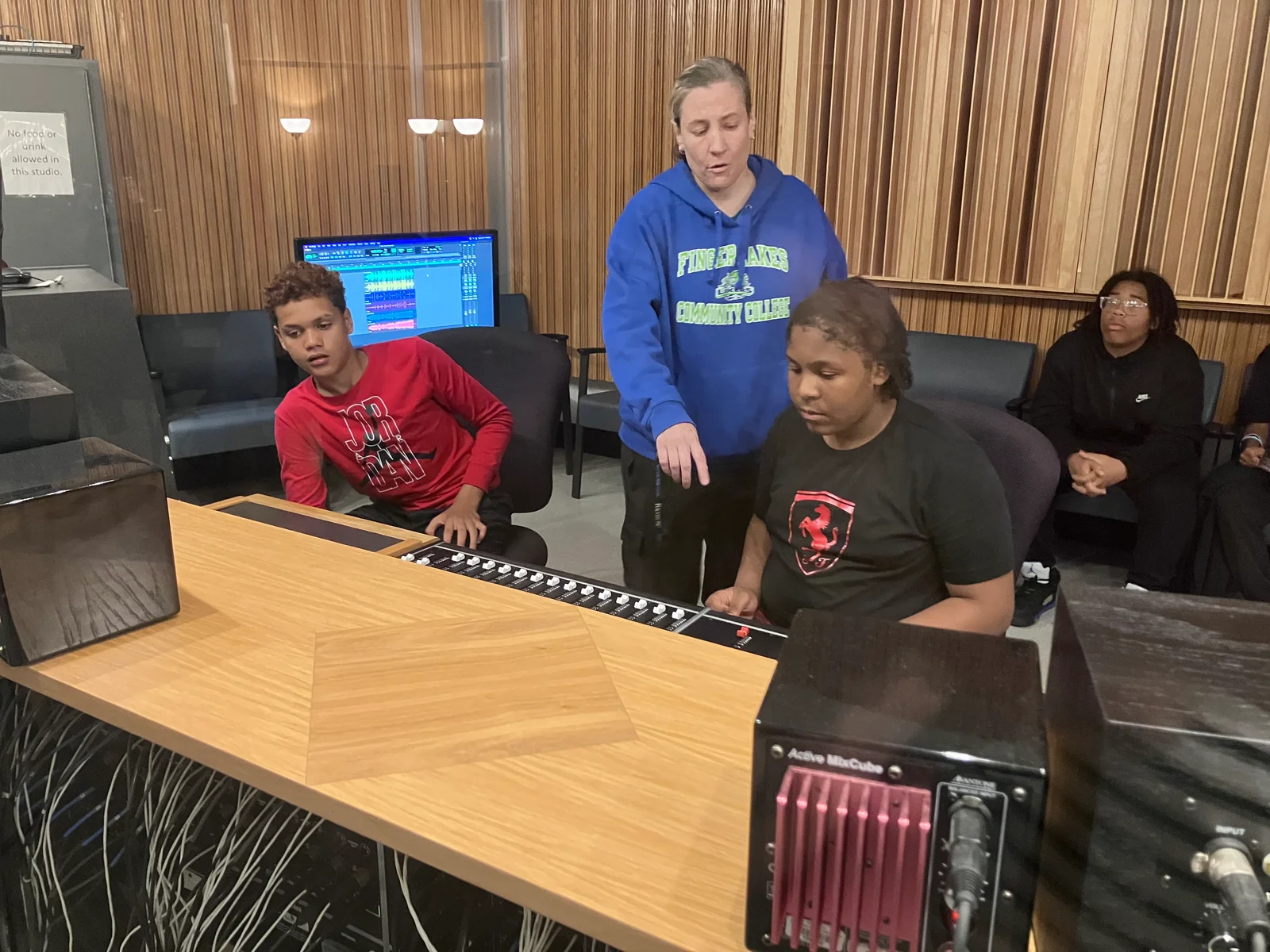 Kari Ripley, technical specialist for the music recording technology program, helps students in the Urban League of Rochester summer camp use a recording console at the main campus.