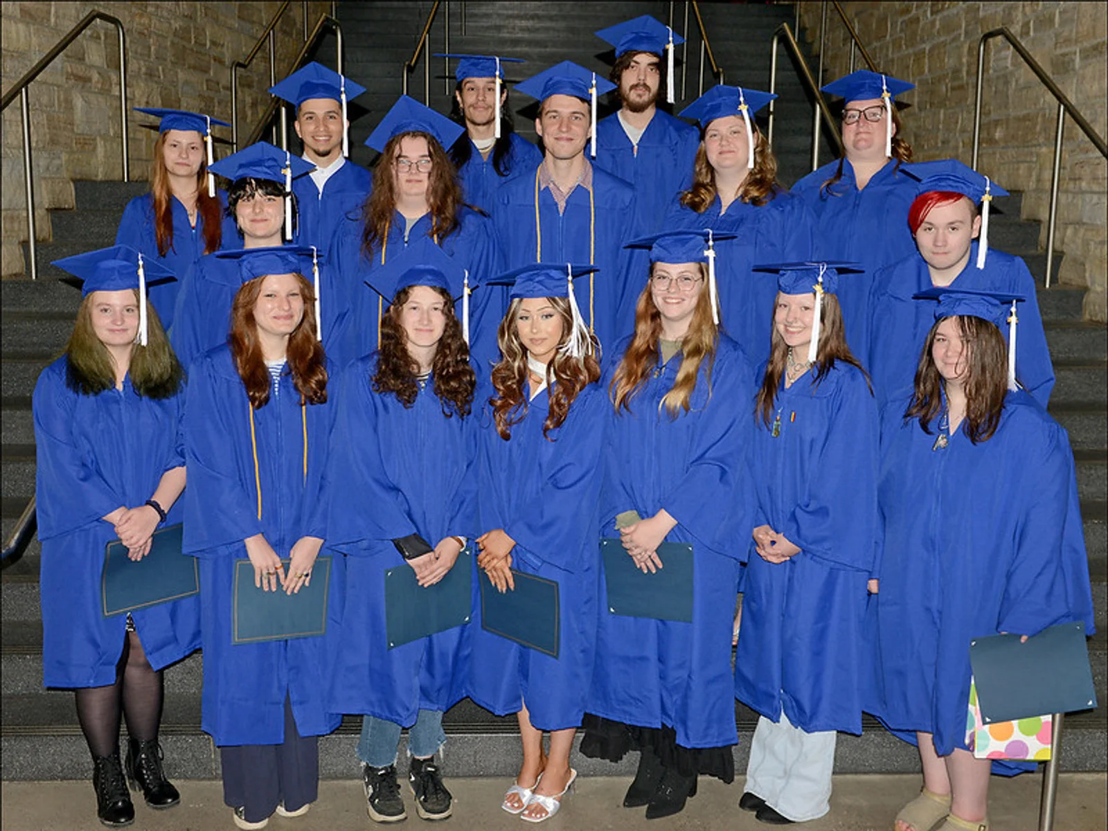 17 graduates in blue caps and gowns