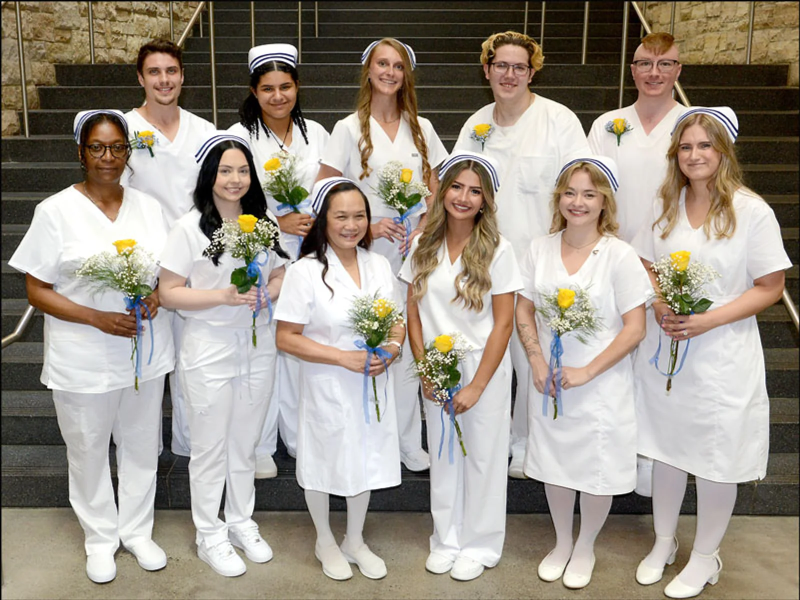 A group of 11 male and female nurses in white uniforms