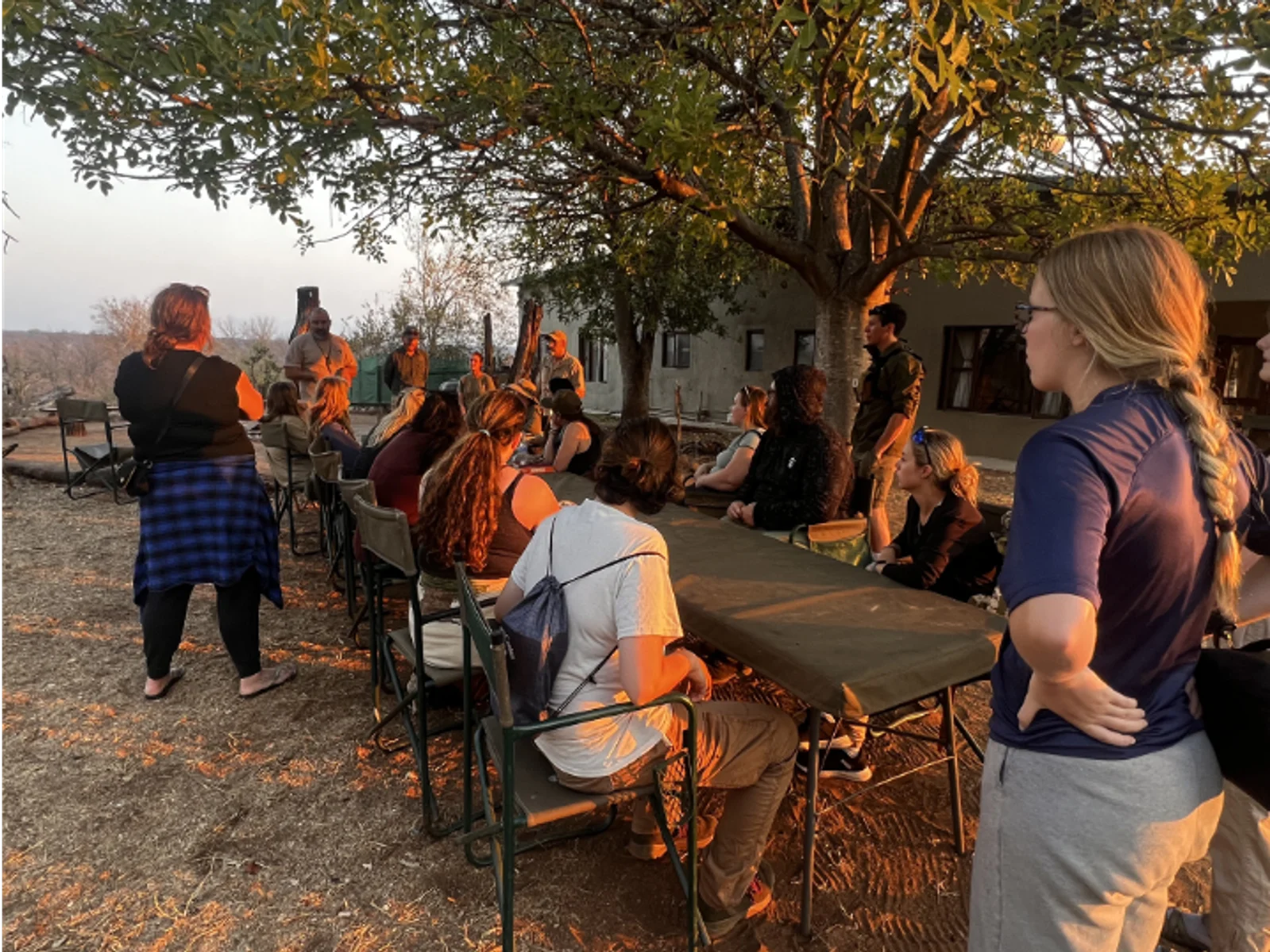 Faculty and students pose for a photo in front of a street sign.