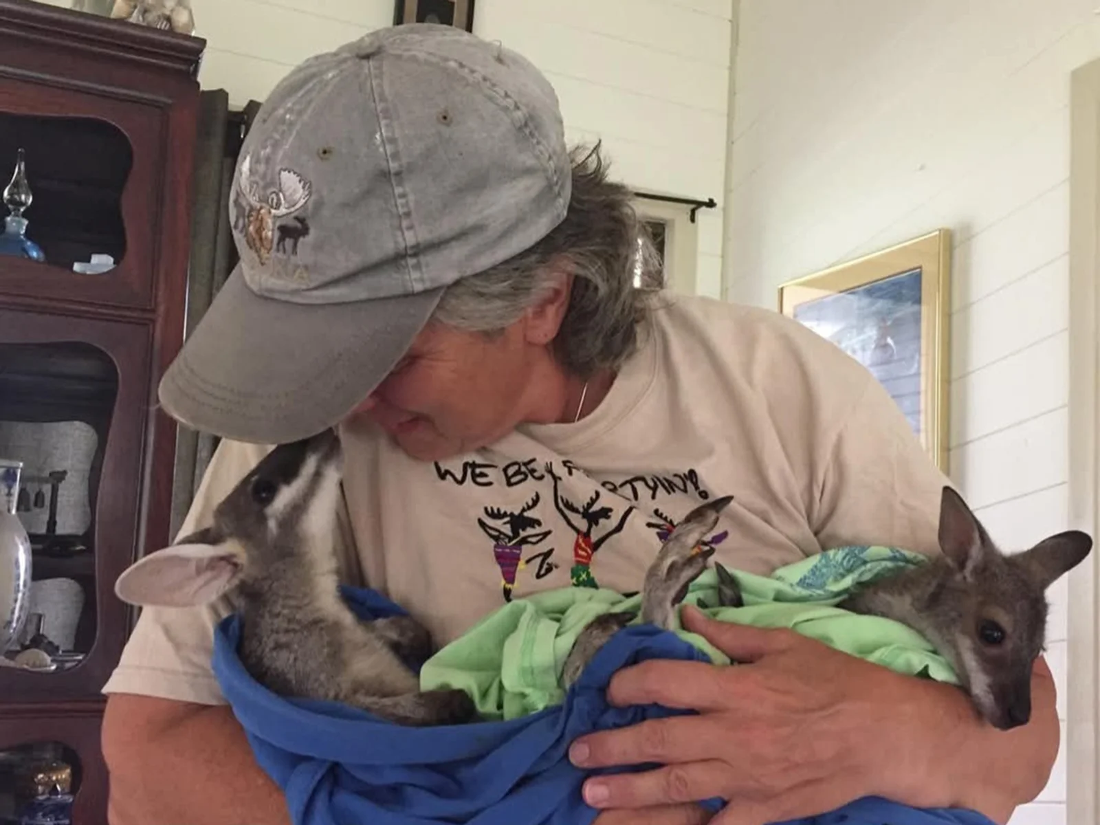 Woman looks down at baby animals she is holding in a blanket