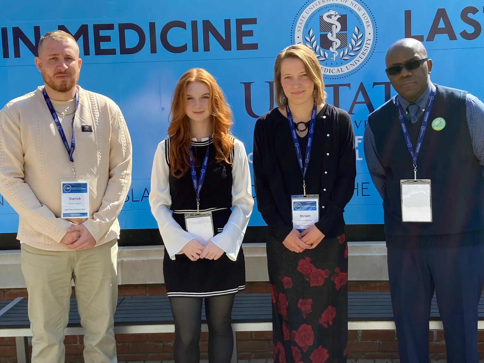 Two men and two women standing in a row wearing conference name tags on lanyards