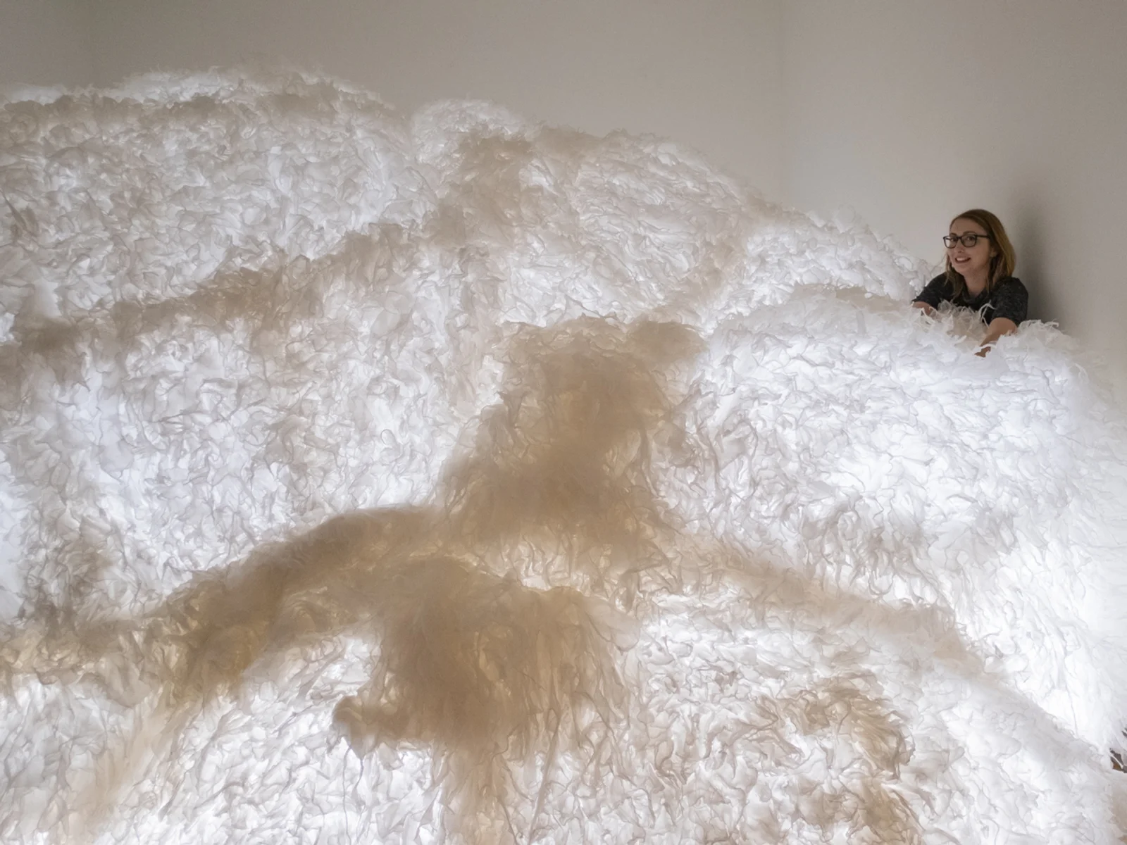 woman behind a large cloudlike art installation