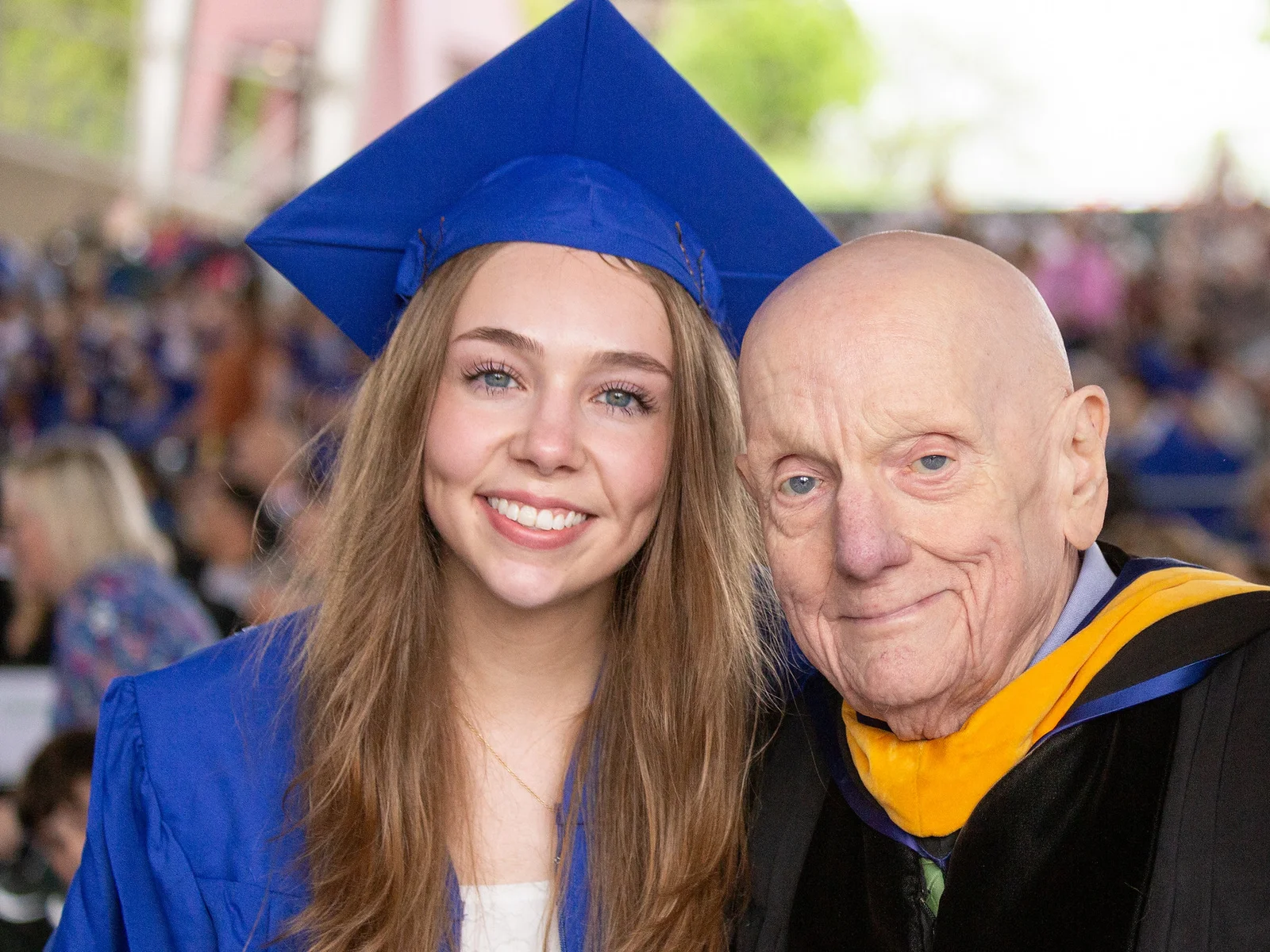 Young woman, older man smiling in commencement regalia