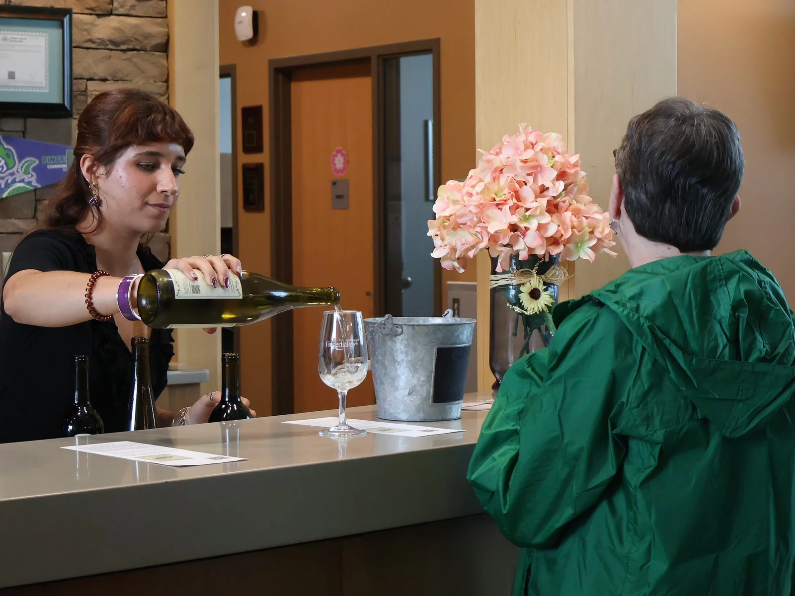 Woman pouring wine at a counter for a customer