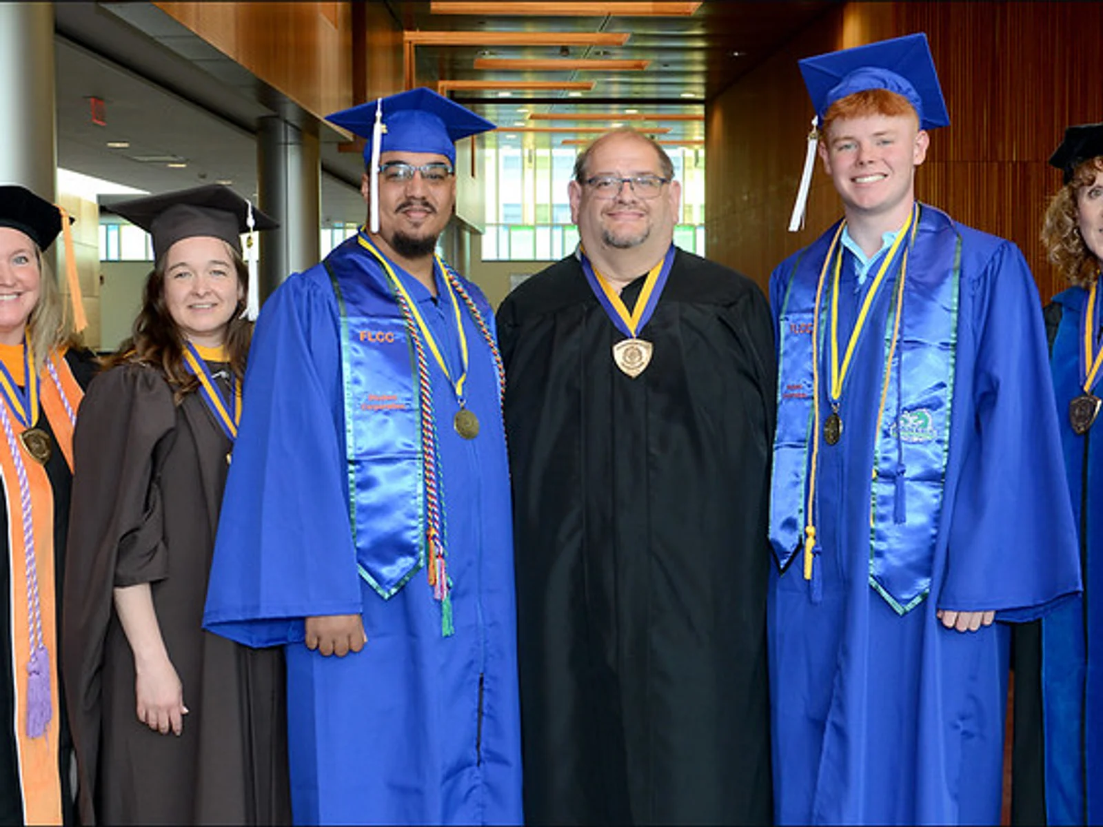 Three men and women posing in academic regalia