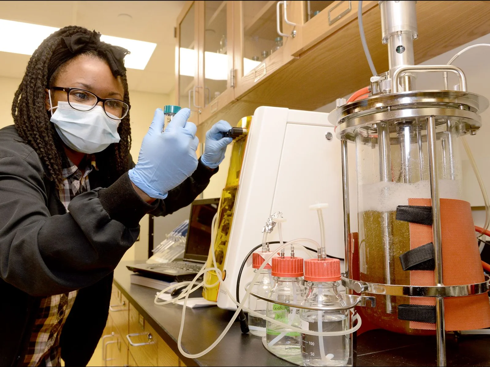 Woman in science lab, inspecting vial
