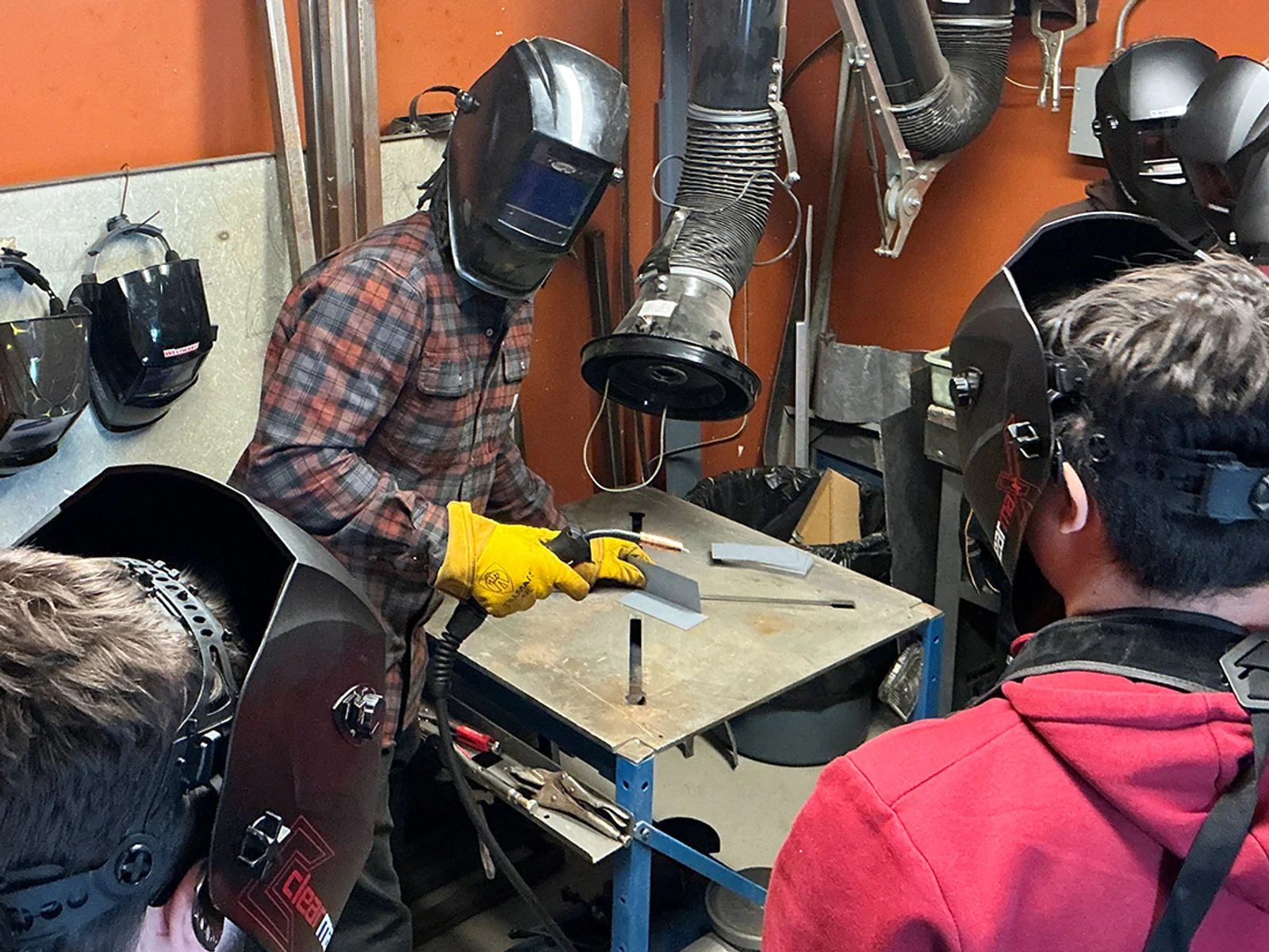 An instructor stands next to a man in a welding helmet using computer simulation technology