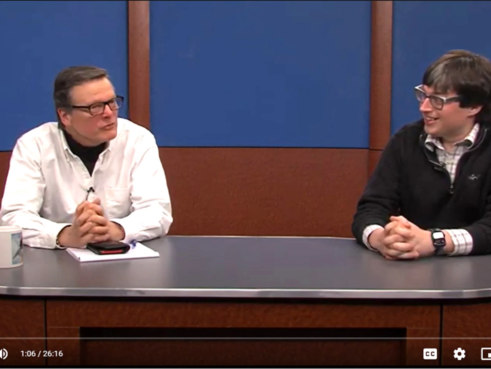 Christopher Parker, Jeff Dugan sitting behind TV studio desk