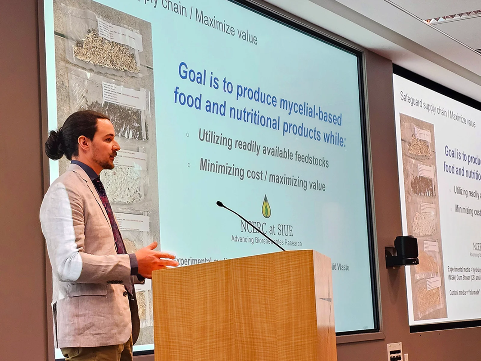 Man at podium giving presentation with slides shown on screen