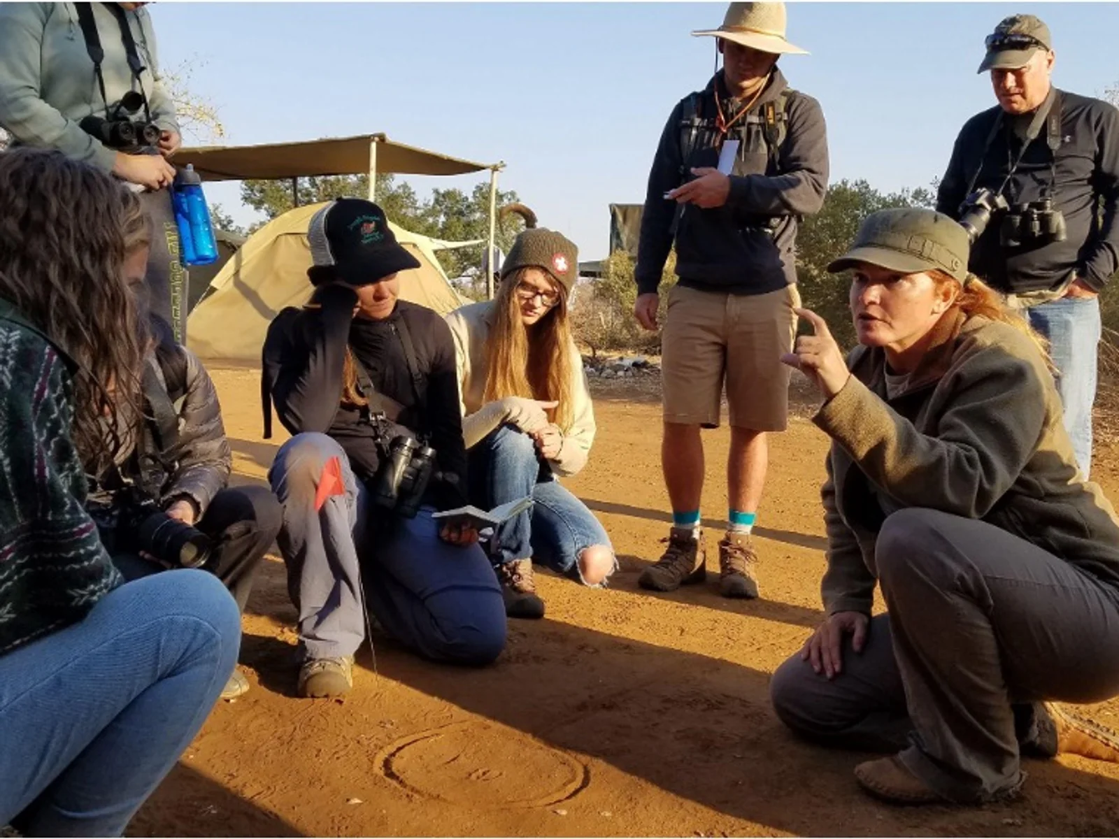 Faculty and students pose for a photo in front of a street sign.
