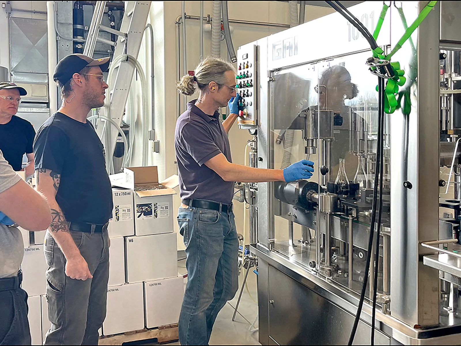 Instructor showing 3 students a wine bottling machine