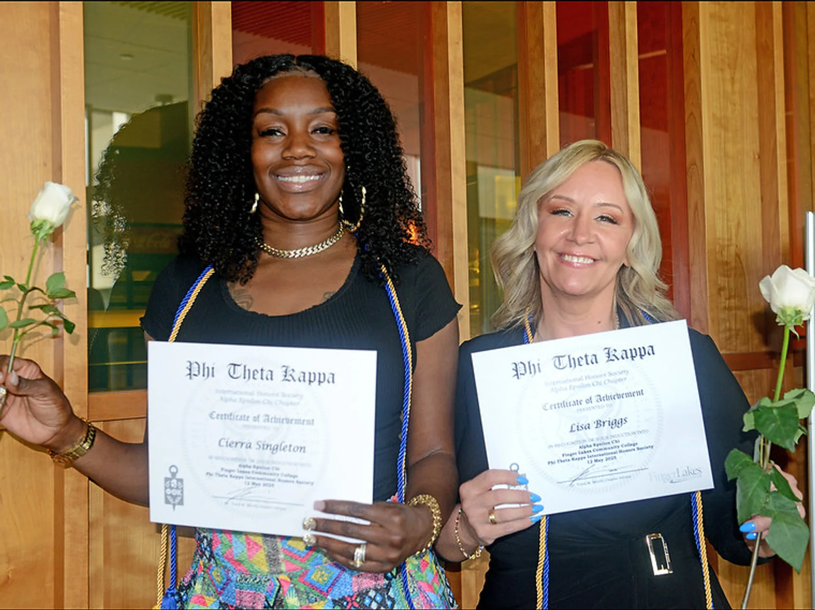 Two women holding honor society certificates